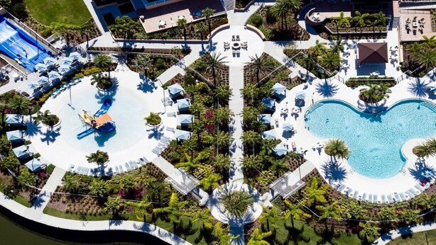 An aerial view of a resort with multiple swimming pools, sun loungers, and palm trees.