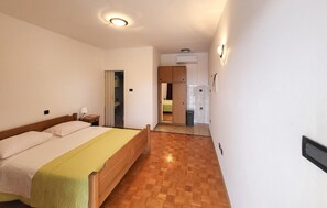A hotel room with a bed, bedside table, and a mirror. There is a bathroom visible through an open door.