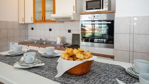 Een keuken met een magnetron, oven en een klok aan de muur.