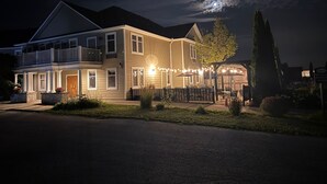 A two-story house with a balcony, string lights, and a well-lit entrance. - Stone Willow Inn (St. Mary's)