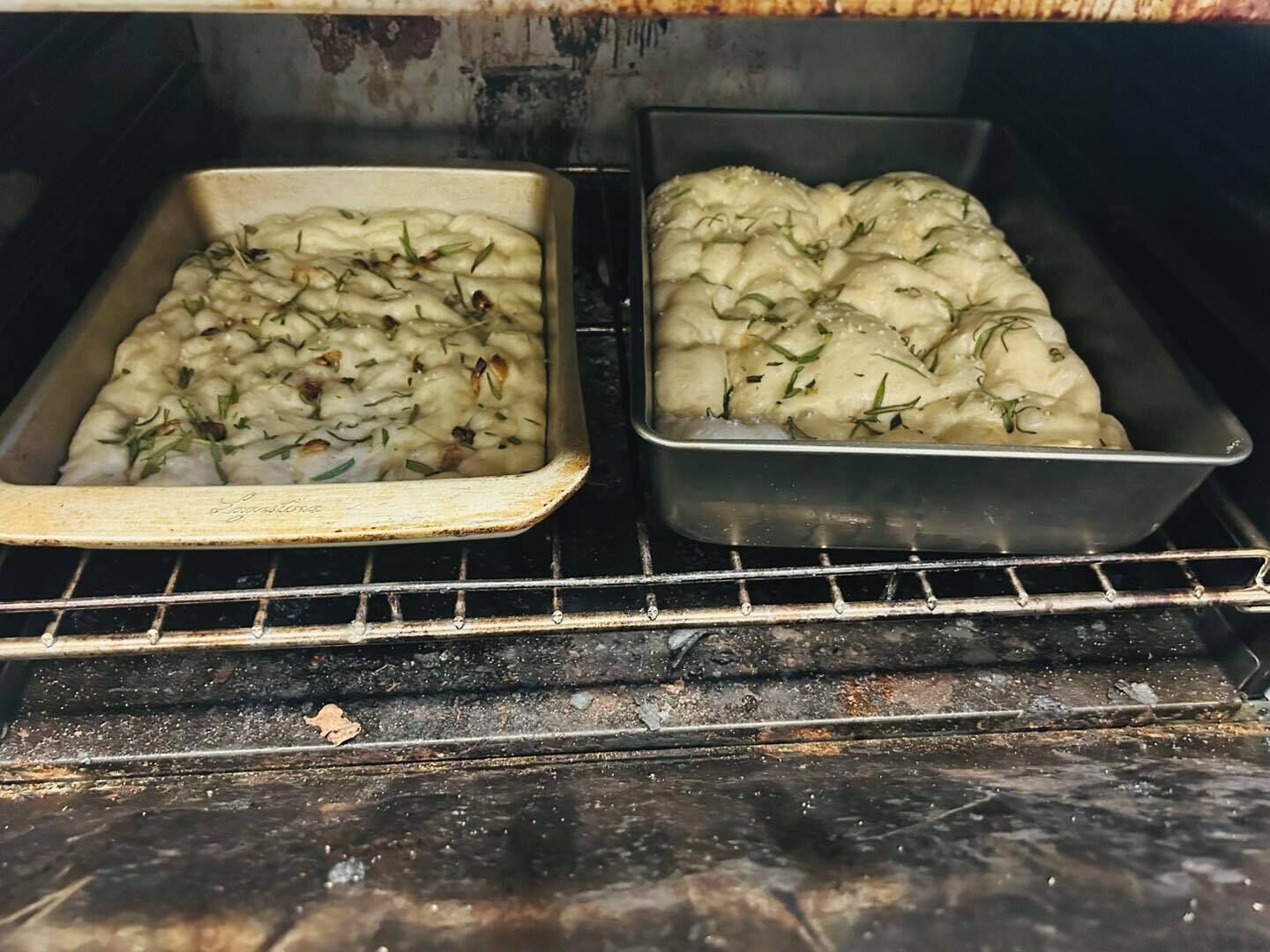 Two baking trays with food in an oven.