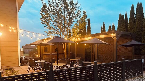 An outdoor patio area with tables and chairs, string lights, and umbrellas. - Stone Willow Inn (St. Mary's)