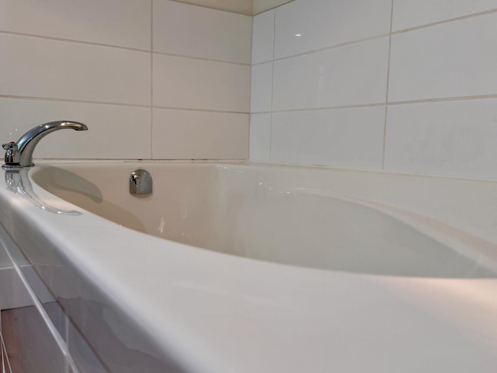 Une salle de bain moderne avec une baignoire sur pieds, des carreaux blancs et un robinet chromé.