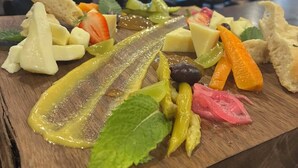 A wooden board with various fruits and vegetables, including a cucumber, carrots, and a piece of bread. - Stone Willow Inn (St. Mary's)