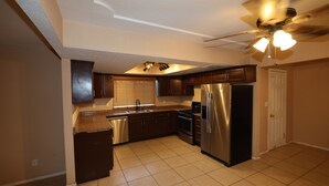 Una cocina con un refrigerador de acero inoxidable, lavavajillas y un ventilador de techo con luces.