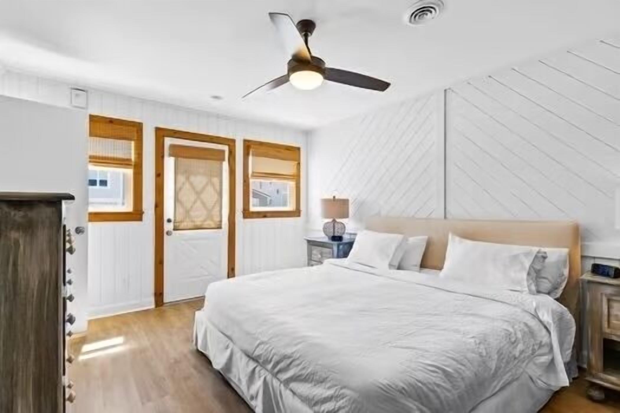 A bedroom with a bed, a ceiling fan, a nightstand, and a window.