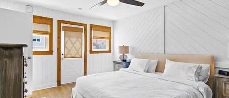 A bedroom with a bed, a ceiling fan, a nightstand, and a window.