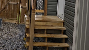 Una escalera de madera que lleva a una casa con revestimiento gris.