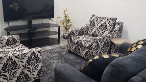 Una sala de estar moderna con un televisor de pantalla plana, un conjunto de sofás y una mesa de centro.