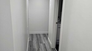 Un pasillo estrecho con suelo de madera y paredes blancas.