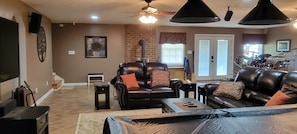 A living room with leather sofas, a coffee table, a fireplace, and a dining area with a drum set. - Cozy & quiet 1 Bedroom apartment with pool table and big screen TV.  (Appomattox)