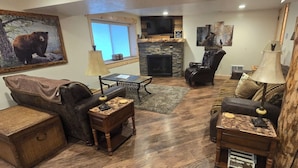 A cozy living room with a fireplace, leather furniture, and a bear painting. - DISCOUNTS BOOK NOW! Beautiful 2 Bedroom Cabin with Great Views! (Island Park)