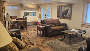 A cozy living room with a sofa, a coffee table, and a dining area with chairs and a table. - DISCOUNTS BOOK NOW! Beautiful 2 Bedroom Cabin with Great Views! (Island Park)