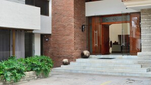Un edificio moderno con facciata in mattoni, grandi porte in legno e una serie di gradini che conducono all'ingresso.