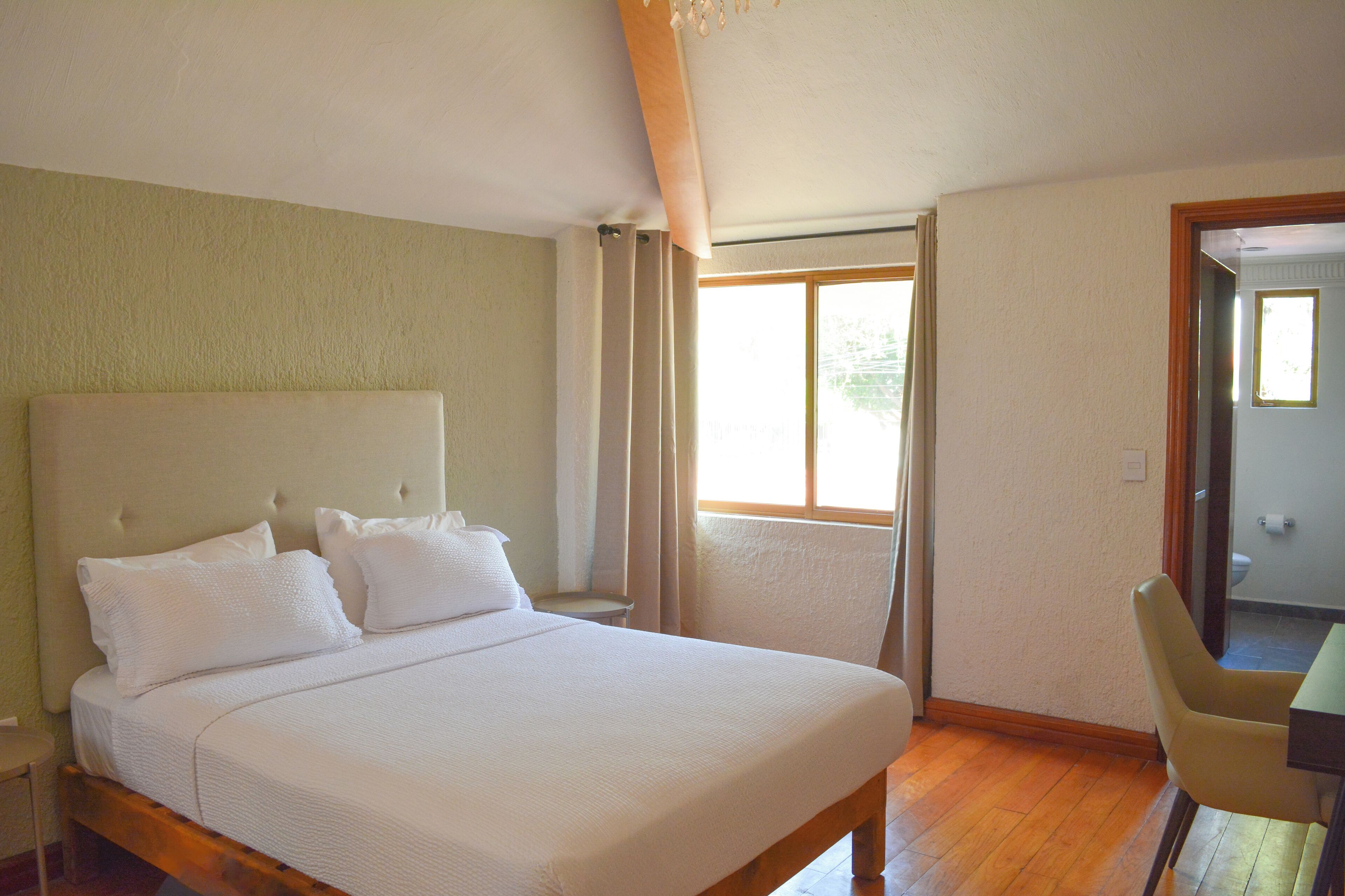 Un dormitorio con una cama grande, una silla y una ventana.