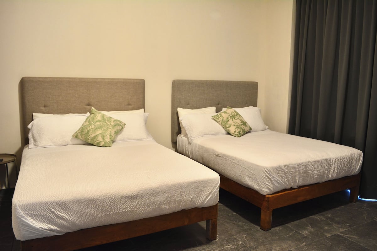 Two twin beds with wooden frames and headboards, each with a white bedspread and a green patterned pillow.
