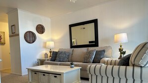 Un salon comprenant un canapé, un fauteuil, une table basse et des éléments de décoration murale.