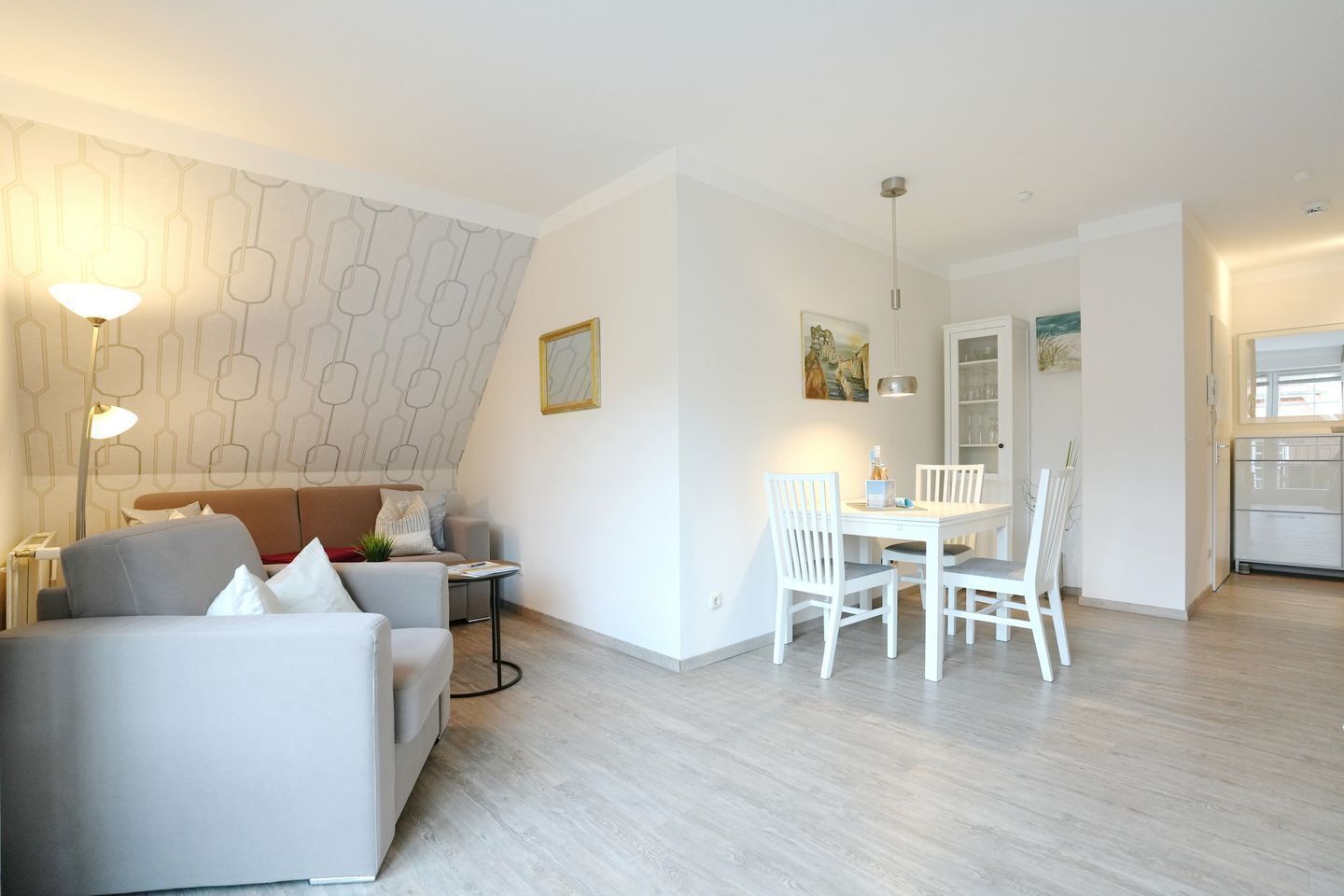 A modern living room with a sofa, a dining table with chairs, and a kitchen area.