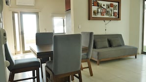Ein modernes Wohnzimmer mit grauem Sofa, Esstisch aus Holz und passenden Stühlen.