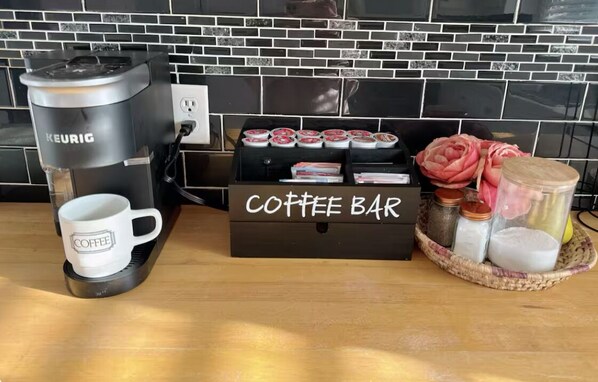 Een koffiezetapparaat, een koffiemok, een koffiebar doos en een mand met potten op een houten tafel.