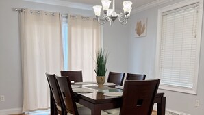 Une salle à manger avec une table et des chaises en bois, un lustre et une plante en pot.