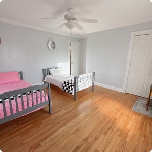 A bedroom with a bed, a crib, a ceiling fan, and a door. - Beautiful and convenient house (Duncan)