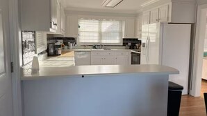 Une cuisine moderne avec des meubles blancs, un îlot central et un lave-vaisselle encastré.