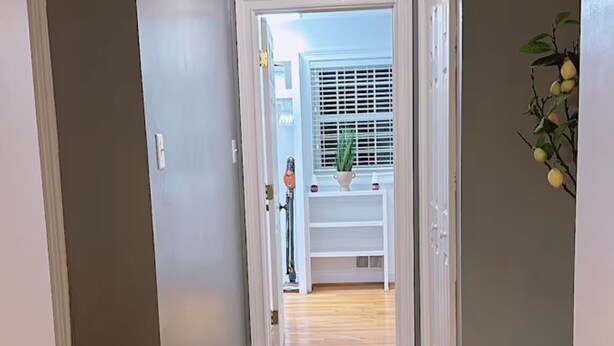 Un couloir avec un plancher en bois, un luminaire au plafond et une pancarte indiquant « buanderie ».