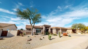 Zona residencial con casas, un árbol y vegetación desértica.