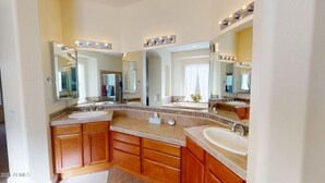 Un baño con dos lavamanos, muebles de madera y espejos grandes con iluminación.
