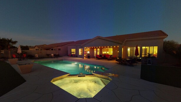 Una piscina con hidromasaje, rodeada de mobiliario exterior y una zona de patio cubierta.