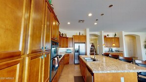 Una cocina amplia con armarios de madera, encimeras de granito y electrodomésticos de acero inoxidable.