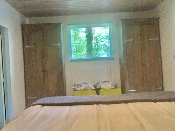 Une chambre à coucher avec un lit, une fenêtre et deux armoires.