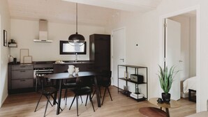A compact kitchen with a dining area, a small round table, and a potted plant. - Mysa Tiny House. At MYSA, every day feels as relaxed as a Sunday morning. (Epe)