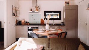 A compact kitchen with a dining area, a TV, and a sofa in the foreground. - GrØn Tiny House in the forest (Epe)
