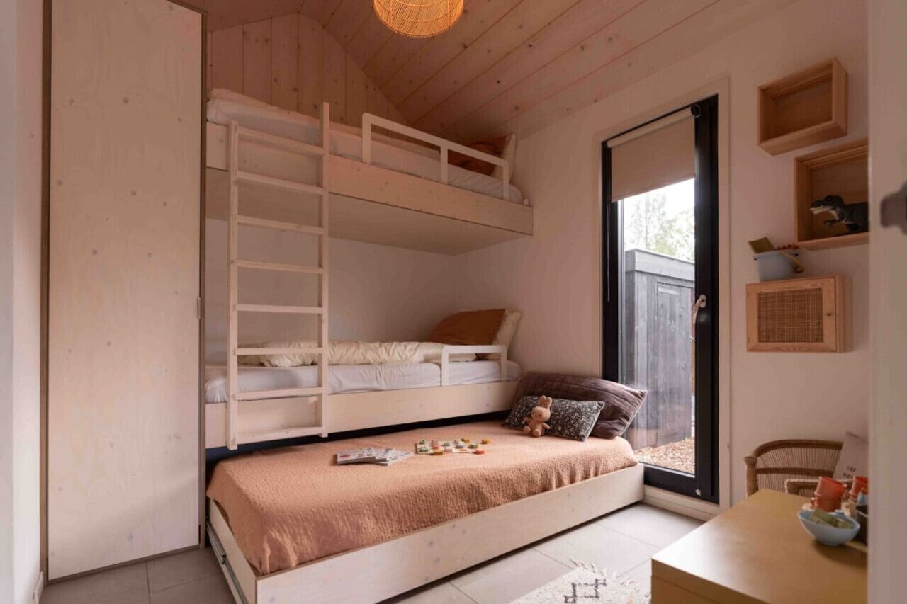 Une chambre confortable avec un lit superposé, une petite table avec un bol, et une fenêtre donnant sur un beau paysage.