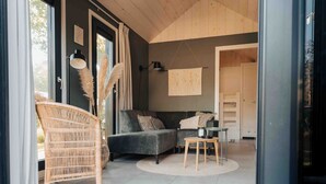 Una sala de estar moderna con un sofá gris oscuro, un sillón de mimbre y una pequeña mesa redonda.