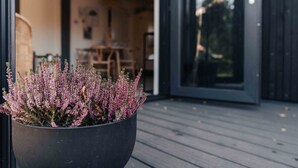 Una terraza de madera con un macetero grande lleno de flores rosas.