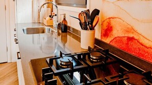 Cozinha moderna com ilha central, eletrodomésticos de aço inoxidável e janela sobre a pia.