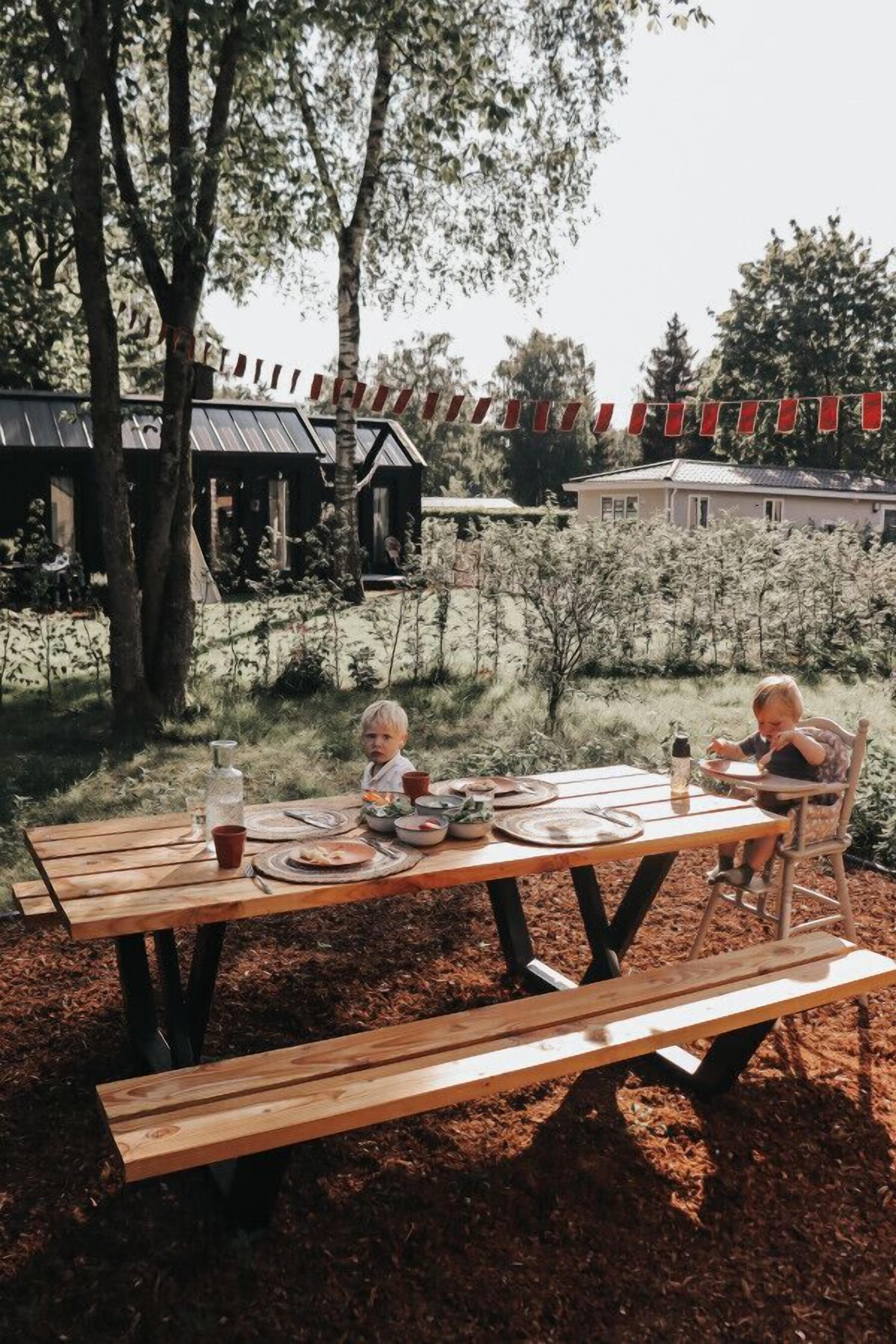 Un tavolo da picnic in legno all'aperto, con un bambino e un adulto.