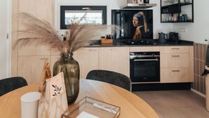 Une cuisine moderne avec des meubles en bois, un plan de travail noir et un téléviseur fixé au-dessus de la cuisinière.