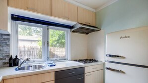 Una cocina moderna con estufa a gas, lavaplatos y un refrigerador Amica blanco.