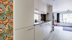 A modern kitchen with white cabinets, a countertop, and a window.