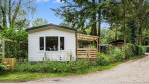 A small, single-story cabin with a wooden porch and a fenced garden area.