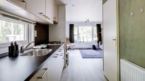 A modern kitchen with a dark countertop, stainless steel sink, and a window overlooking a garden.