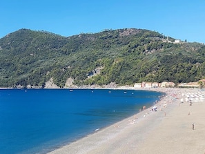 A beach with clear blue water, a sandy shore, and a forested hill in the background. - Silent Bay Historical by Interhome (Sestri Levante)