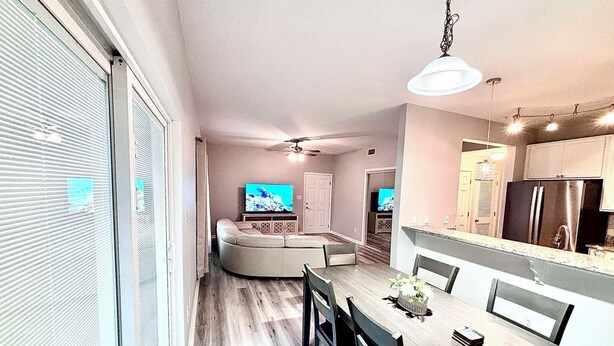 A modern kitchen with a dining area, a large TV, and a ceiling fan. - Luxury and comfy GS condo on the first floor. (Gulf Shores)
