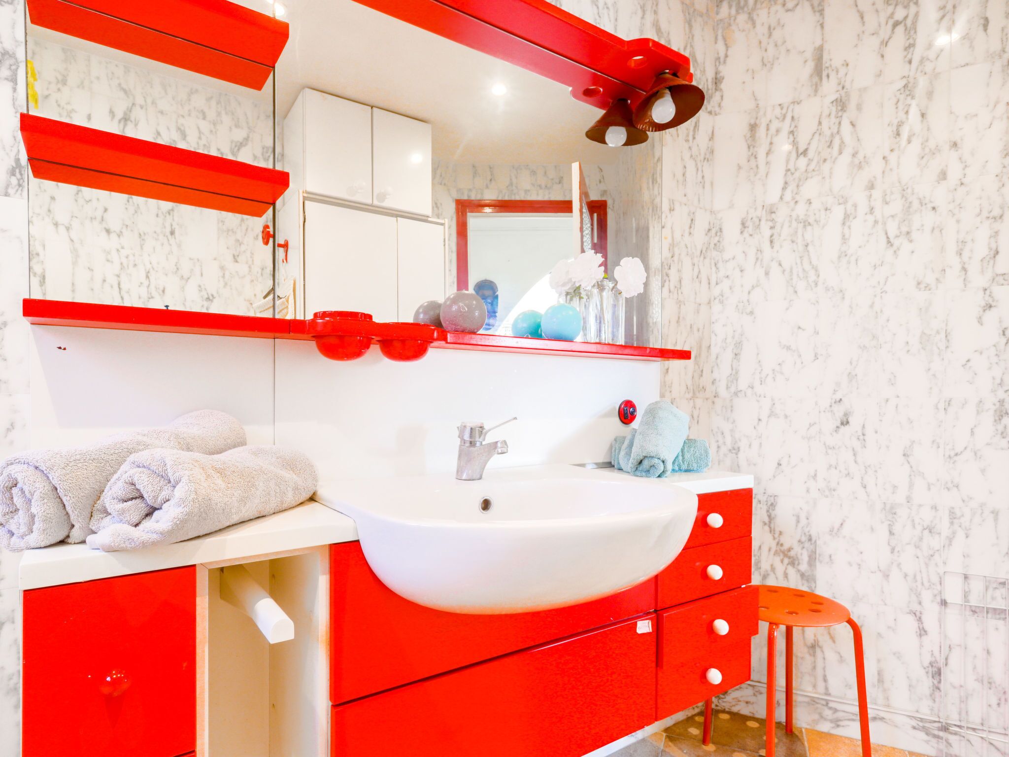 A bathroom with a white sink, red cabinets, and a mirror.