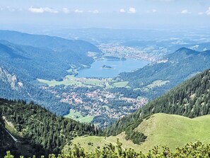 Ein weiter Panoramablick über ein Tal mit einem See, umgeben von bewaldeten Hügeln und einer kleinen Stadt.