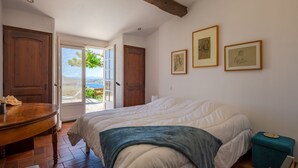 Un dormitorio con una cama grande, puerta de madera y vistas al exterior.